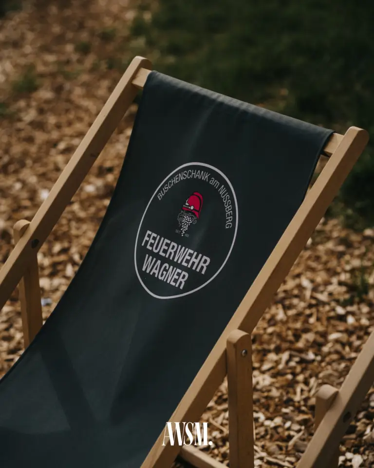 Liegestuhl mit dem Logo des Buschenschanks Feuerwehr Wagner am Nussberg auf Holzhackschnitzeln – Vineyard Edition, 24.05.2025