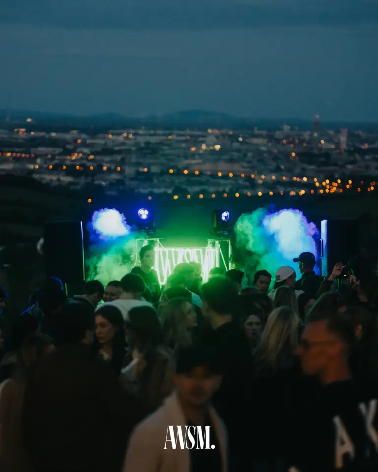 Tanzende Menge vor dem DJ-Pult mit AWSM-Neonschild und blauem Nebel, dahinter die Lichter von Wien am Abend – Vineyard Edition, 24.05.2025