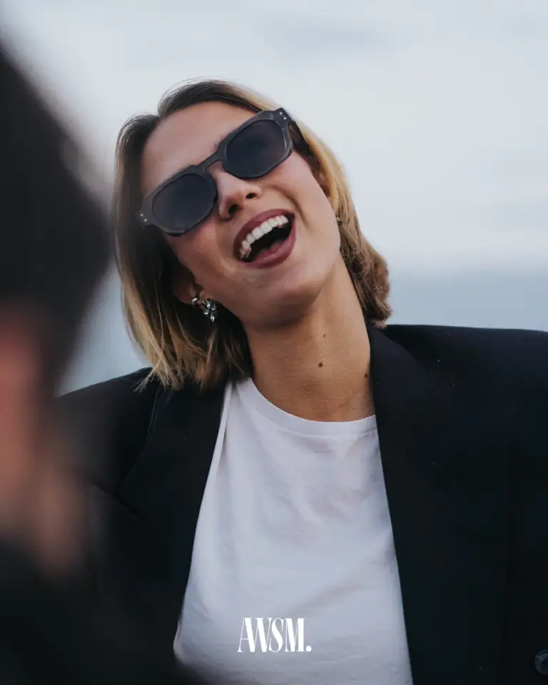 Lachender Gast mit dunkler Sonnenbrille und schwarzem Blazer legt den Kopf zurück, vor hellem Himmel – Vineyard Edition, 24.05.2025
