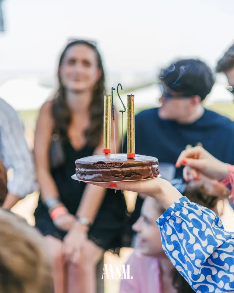 Schokoladetorte mit goldenen Tischfontänen wird hochgehalten, dahinter unscharf sitzende Gäste im Hellen – Vineyard Edition, 14.06.2025