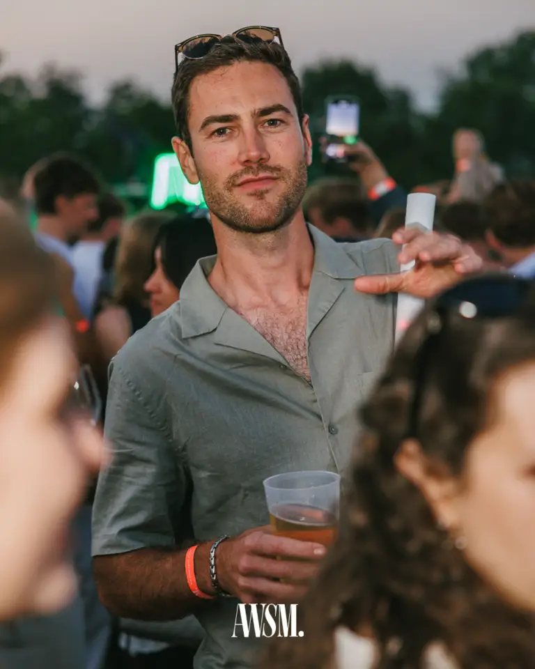 Gast im Hemd mit Becher in der Hand inmitten der Menge, hinten Handys in der Luft und grünes Licht am Abend – Vineyard Edition, 14.06.2025