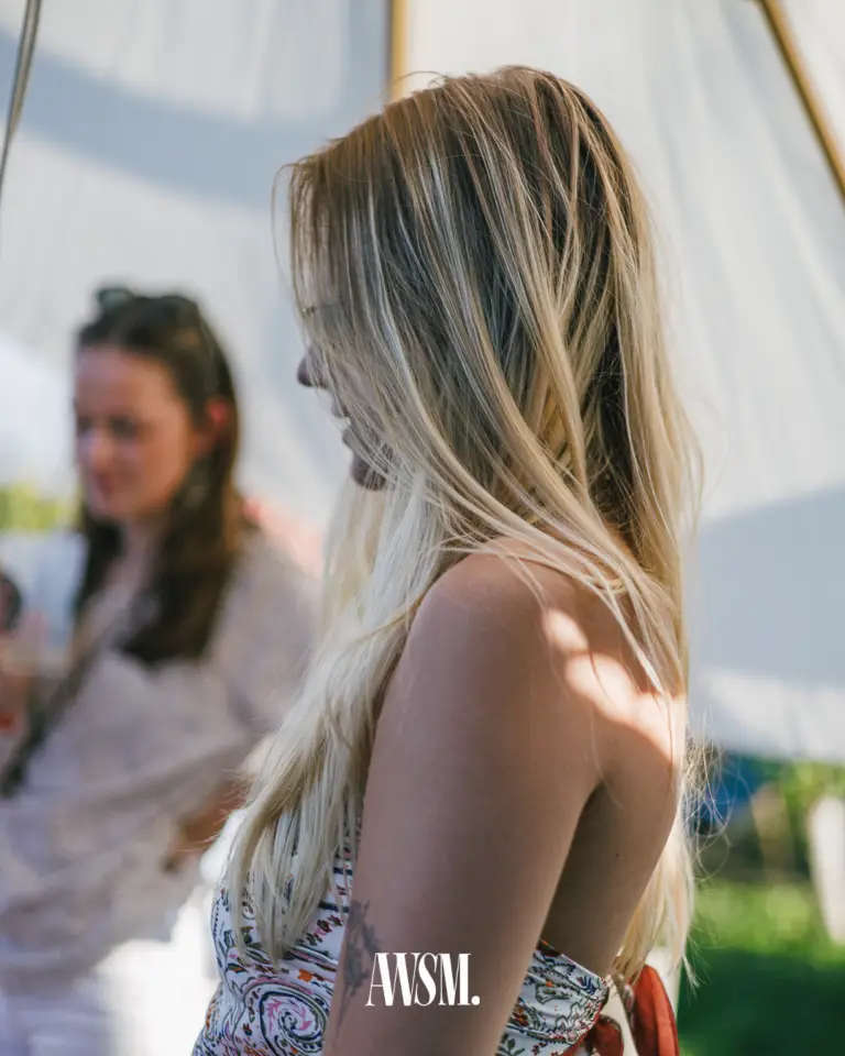 Gast mit langen blonden Haaren im Profil vor einem hellen Zeltdach, im Hintergrund unscharf ein weiterer Gast – Vineyard Edition, 14.06.2025