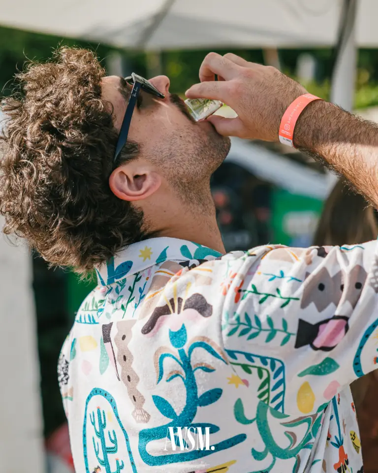 Gast mit Sonnenbrille und bunt gemustertem Hemd trinkt einen Shot, Festivalband am Handgelenk – Vineyard Edition, 14.06.2025