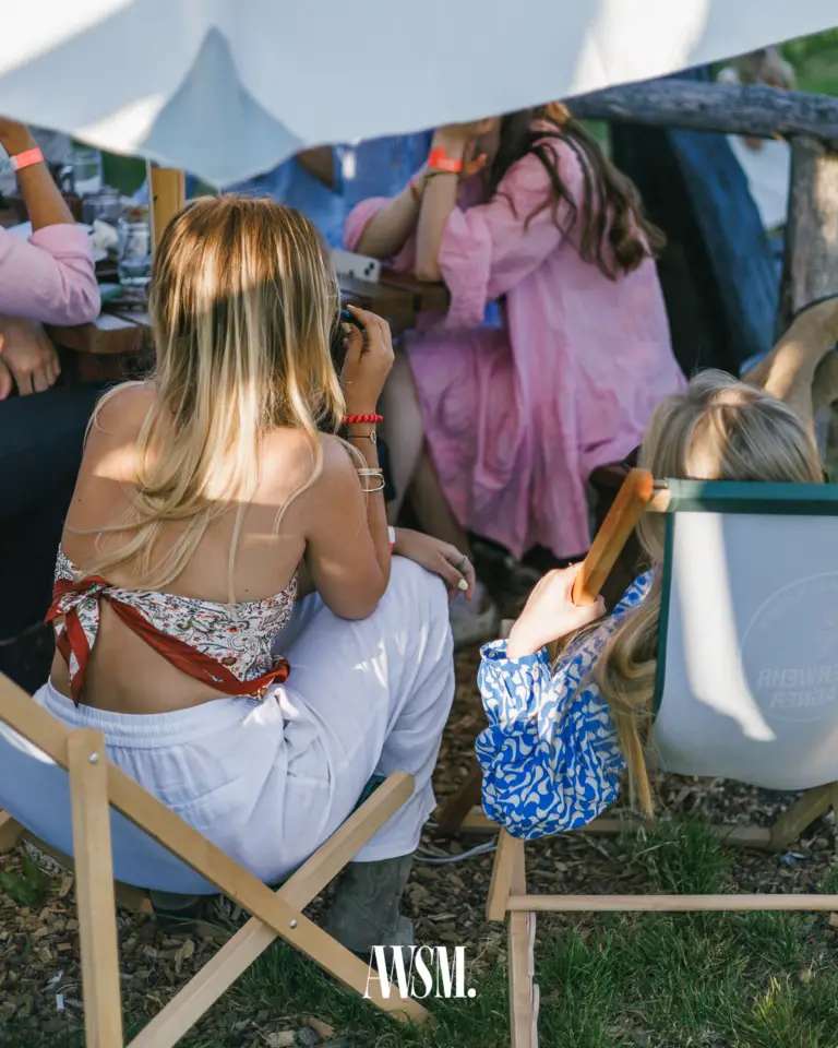 Gäste sitzen in Liegestühlen im Schatten eines Sonnensegels auf Rindenmulch, von hinten gesehen – Vineyard Edition, 14.06.2025