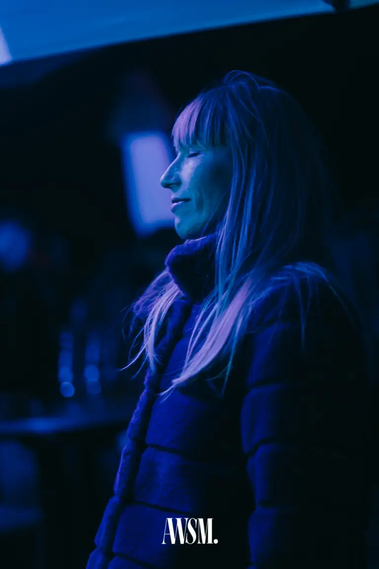Gast mit Pony und langem Haar schließt lächelnd die Augen, in blauem Licht am Nussberg – Vineyard Edition, 04.10.2025