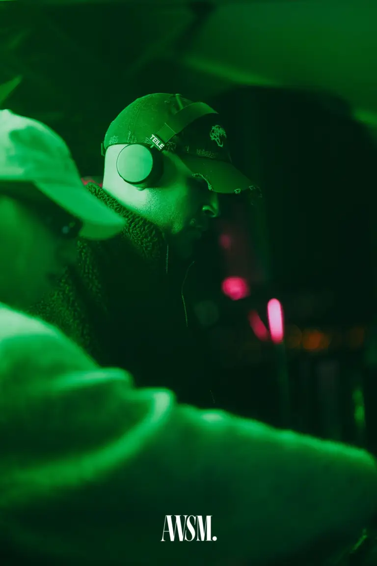 DJ mit Kappe und Kopfhörern legt in grünem Licht auf, davor ein unscharfer Gast – Vineyard Edition, 04.10.2025