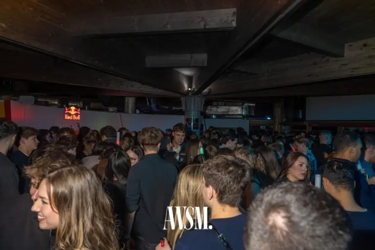 Dicht gefüllter Saal unter der dunklen Holzdecke, Gäste stehen in Gruppen und unterhalten sich – NYE Skyline Edition, 31.12.2025