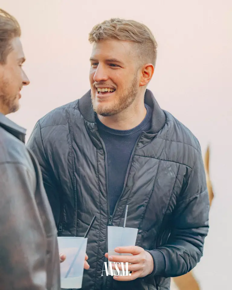 Mann in Steppjacke lacht mit einem Becher in der Hand im Gespräch im Freien – Grand Vineyard Opening, 11.04.2026