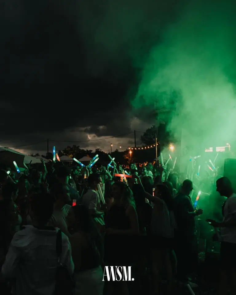 Green haze drifts over the crowd with colourful glow sticks, dark clouds and string lights above on the Nussberg – Vineyard Summer, 18 July 2026