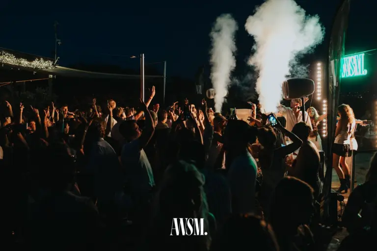 Nebelfontänen schießen neben dem DJ-Pult in den Nachthimmel, Menge mit erhobenen Armen, rechts die AWSM-Leuchtschrift – Skyline Edition, 08.08.2026
