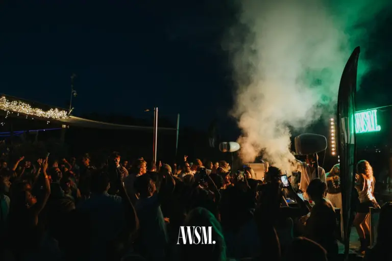 Menge feiert bei Nacht vor dem DJ-Pult, grün angestrahlte Nebelwolke und AWSM-Leuchtschrift, links Lichterketten – Skyline Edition, 08.08.2026