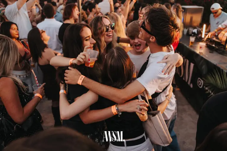 Gruppe umarmt sich lachend vor dem DJ-Pult im Abendlicht, rundum Gäste mit Bechern, rechts legt der DJ auf – Skyline Edition, 08.08.2026
