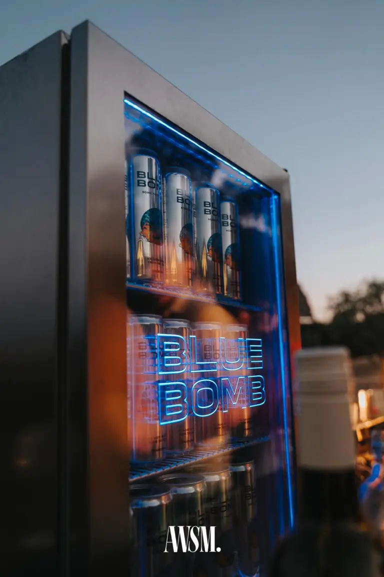 Blau beleuchteter Getränkekühlschrank voller Dosen im Freien, dahinter Abendhimmel und Baumkronen – Skyline Edition, 08.08.2026