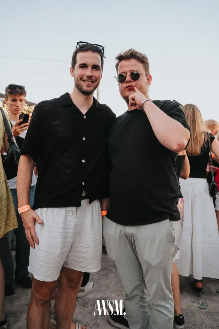 Zwei Männer in schwarzen Hemden posieren nebeneinander, einer lächelt, der andere mit runder Sonnenbrille – Skyline Edition, 08.08.2026