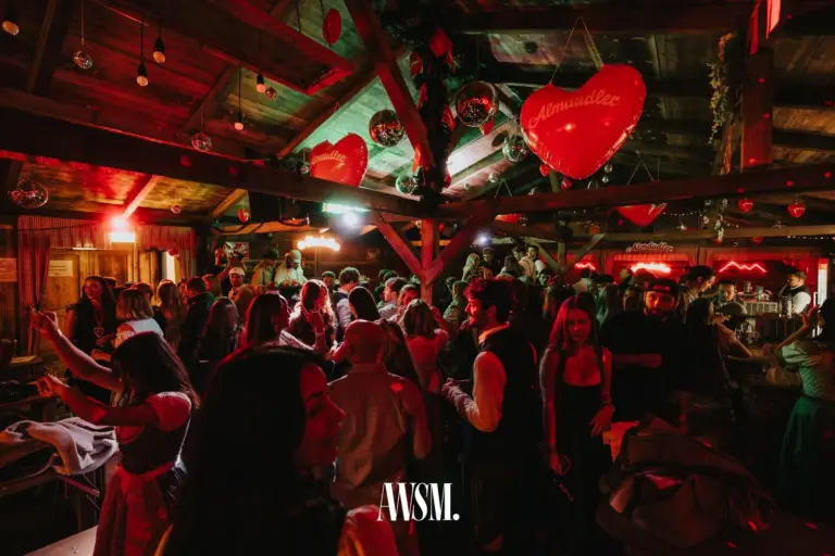 Volle Tanzfläche unter dem Holzdach mit großen roten Herzballons, Discokugeln und Gästen in Dirndl und Tracht – AWSM. GOES KAISER WIESN, 27.09.2026
